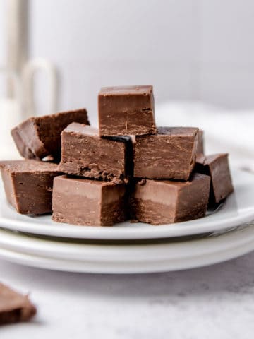 A pile of 2 ingredient fudge squares on a white plate.