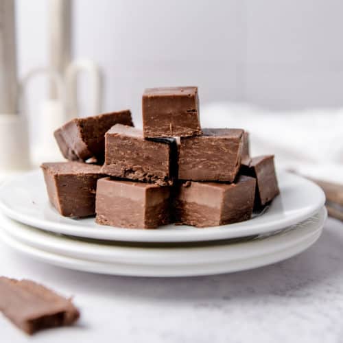A pile of 2 ingredient fudge squares on a white plate.