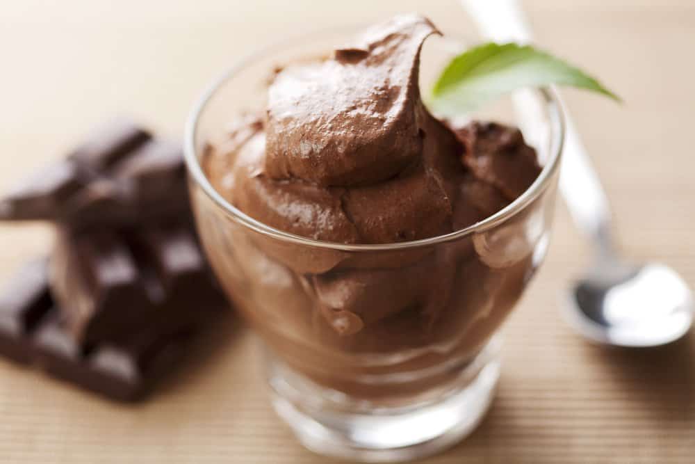 A closeup of fresh chocolate mousse in a glass with a spoon.
