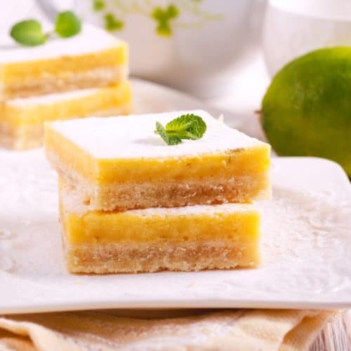 Two lime pie bars on a white plate.