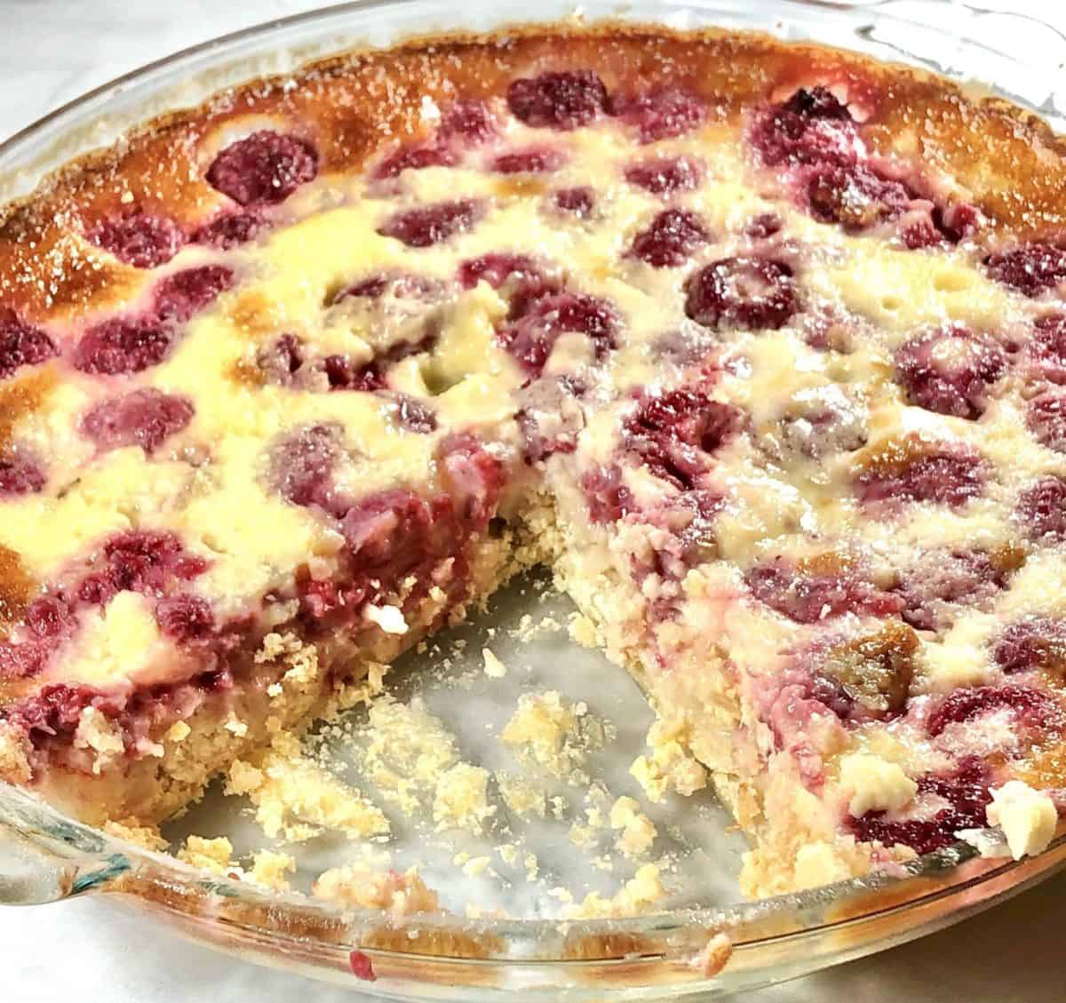 A close up of German raspberry custard kuchen with a slice missing.