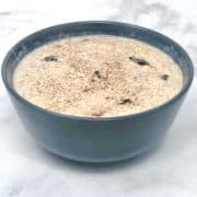 A bowl of cinnamon raisin rice pudding dessert on the table.