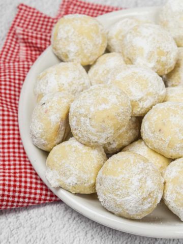 A pile of pecan snowball cookies on a plate.