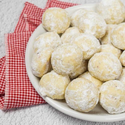 A pile of pecan snowball cookies on a plate.