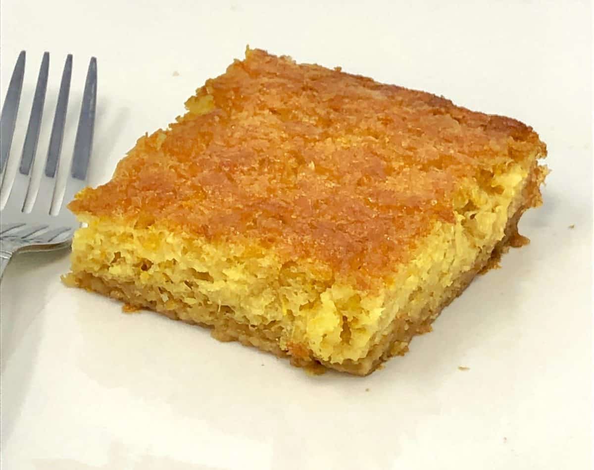 A close up piece of Greek orange pie on a plate with a fork.