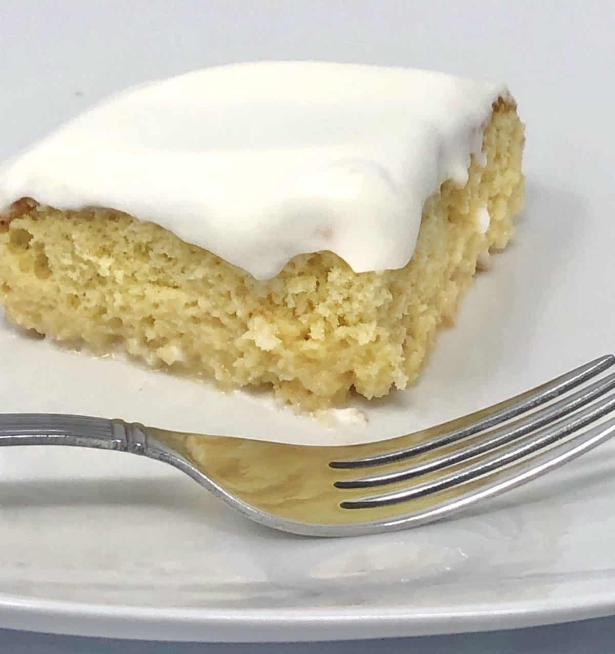 A close up of a piece of shortcut tres leches cake on a plate with a fork.