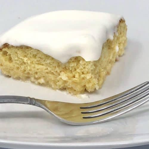 A close up of a piece of shortcut tres leches cake on a plate with a fork.