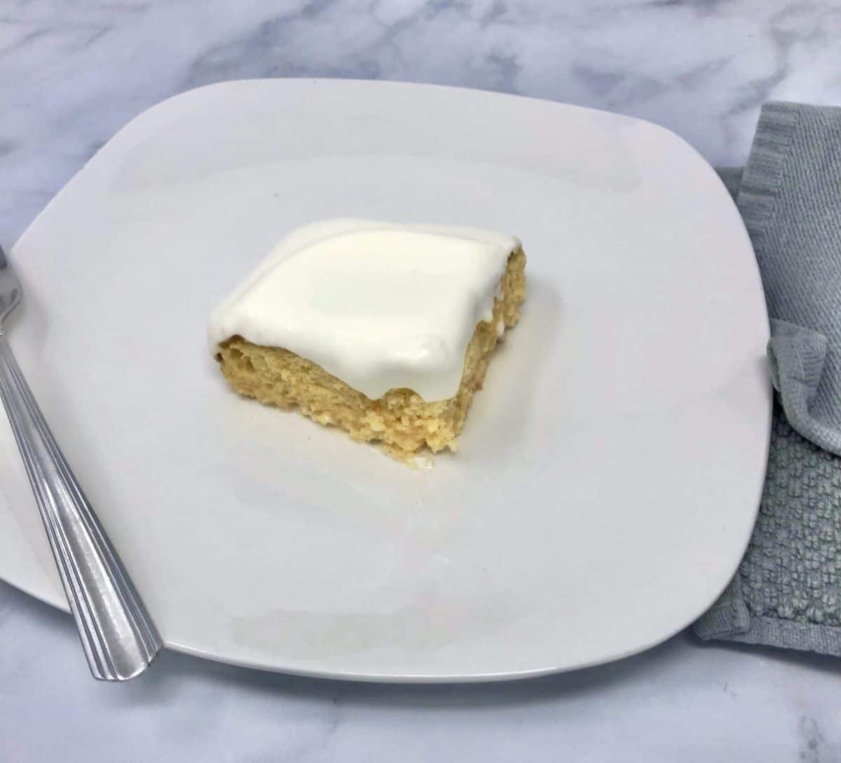A piece of shortcut tres leches cake on a plate with a fork.