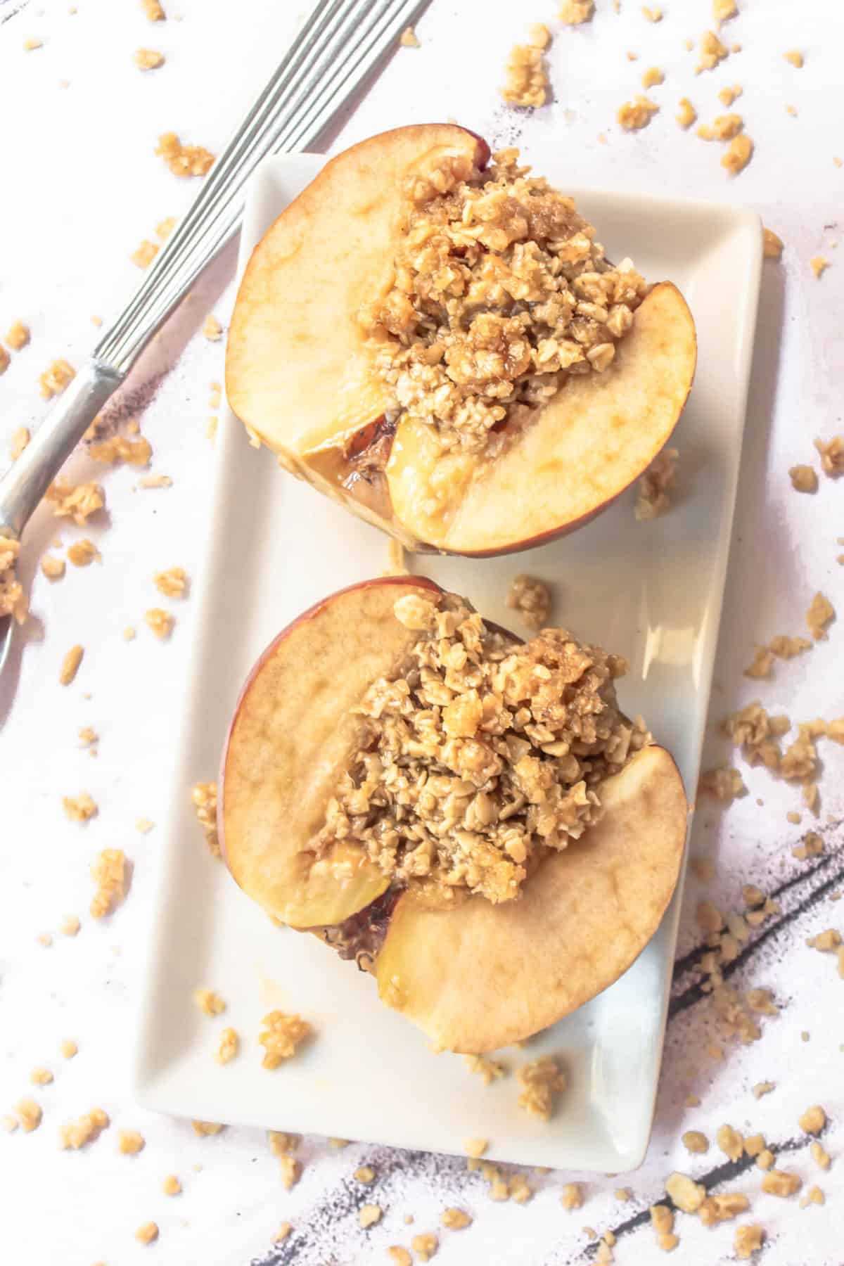 Two stuffed baked apples with oatmeal filling on a plate.
