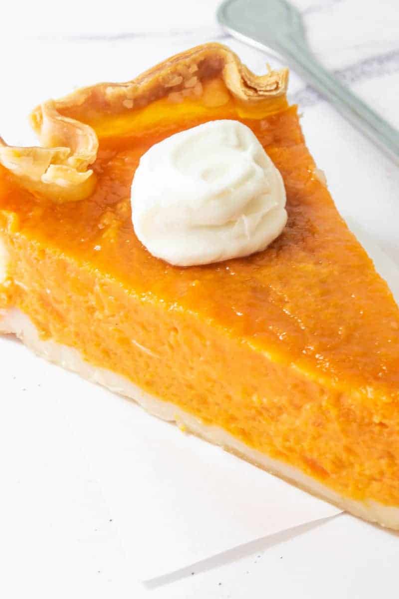 A close up for sweet potato pie with whipped cream on the top of it.