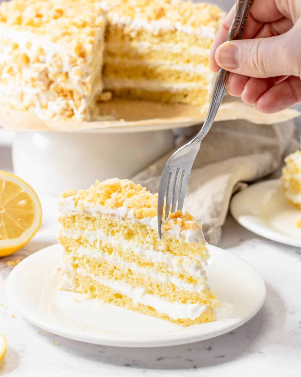 A fork pushing down into a slice of lemon crunch cake.