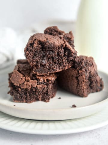 Three almond flour brownies in a pile on a plate.