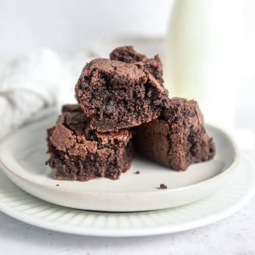 Three almond flour brownies in a pile on a plate.