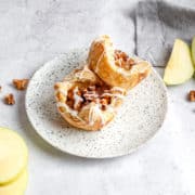 Two apple pie puff pastries on a plate ready to eat.