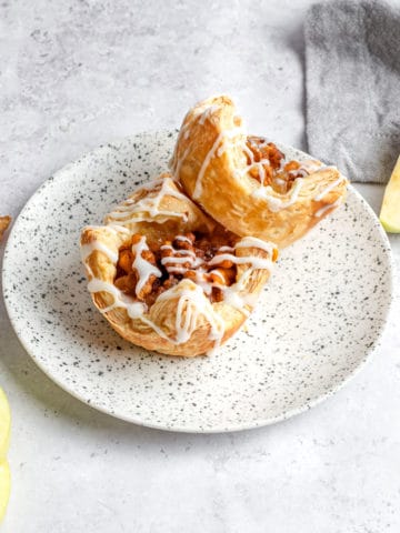 Two apple pie puff pastries on a plate ready to eat.