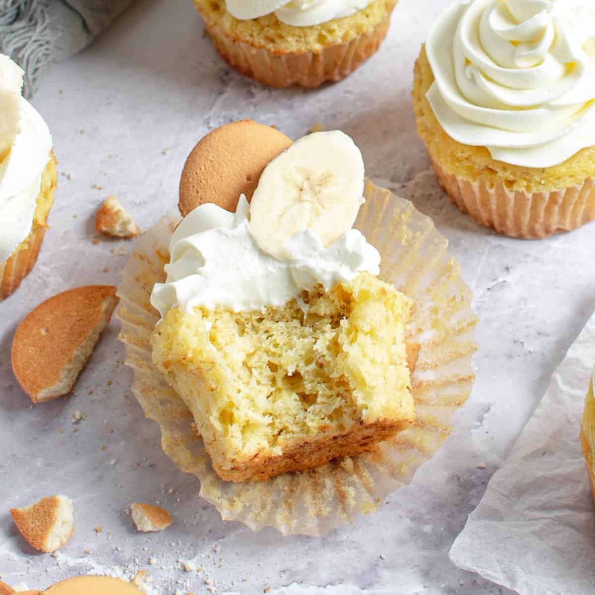 A banana cream cupcake with a bit taken out of it.