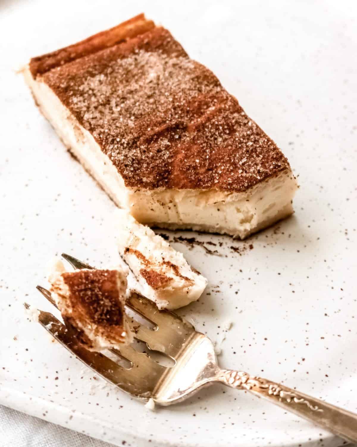 A bite of cheesecake on a plate with a fork.