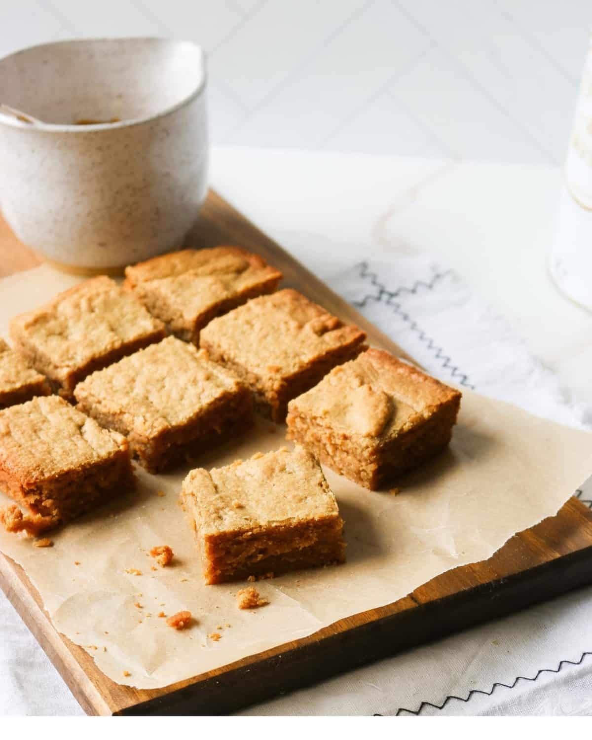 Several blondies on a wooden cutting board.