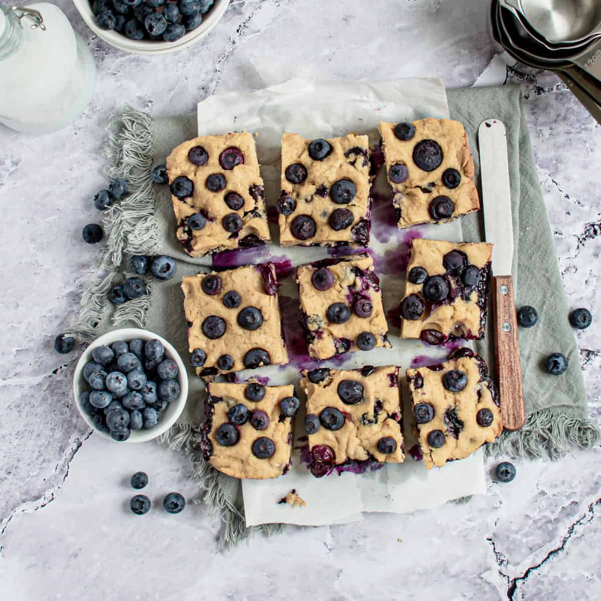 Nine blueberry blondies spread out on a table.