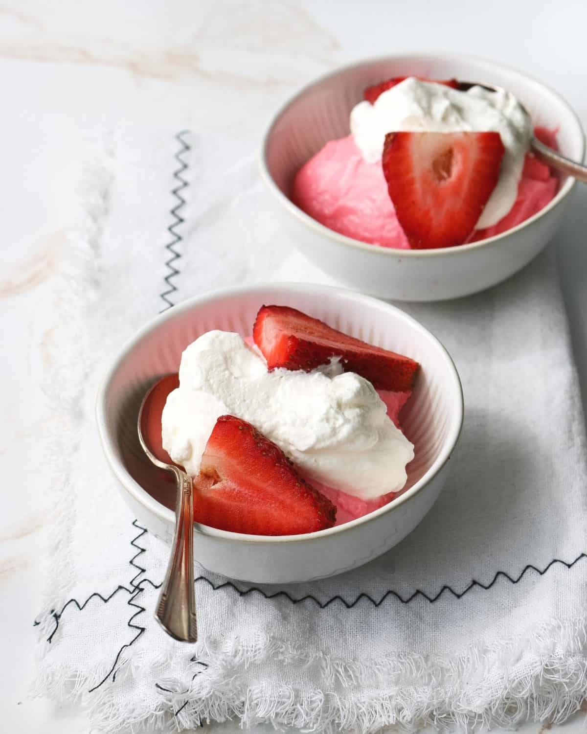 Two servings of pudding with fresh strawberries.