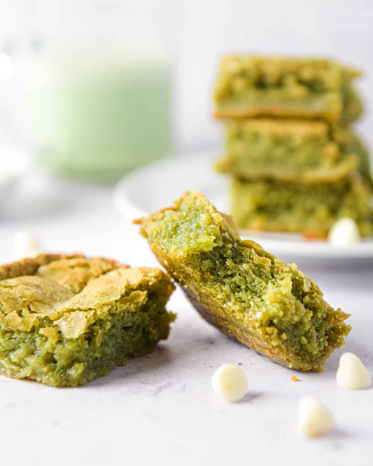 A matcha brownie with a bite taken out of it with white chocolate chips around it.
