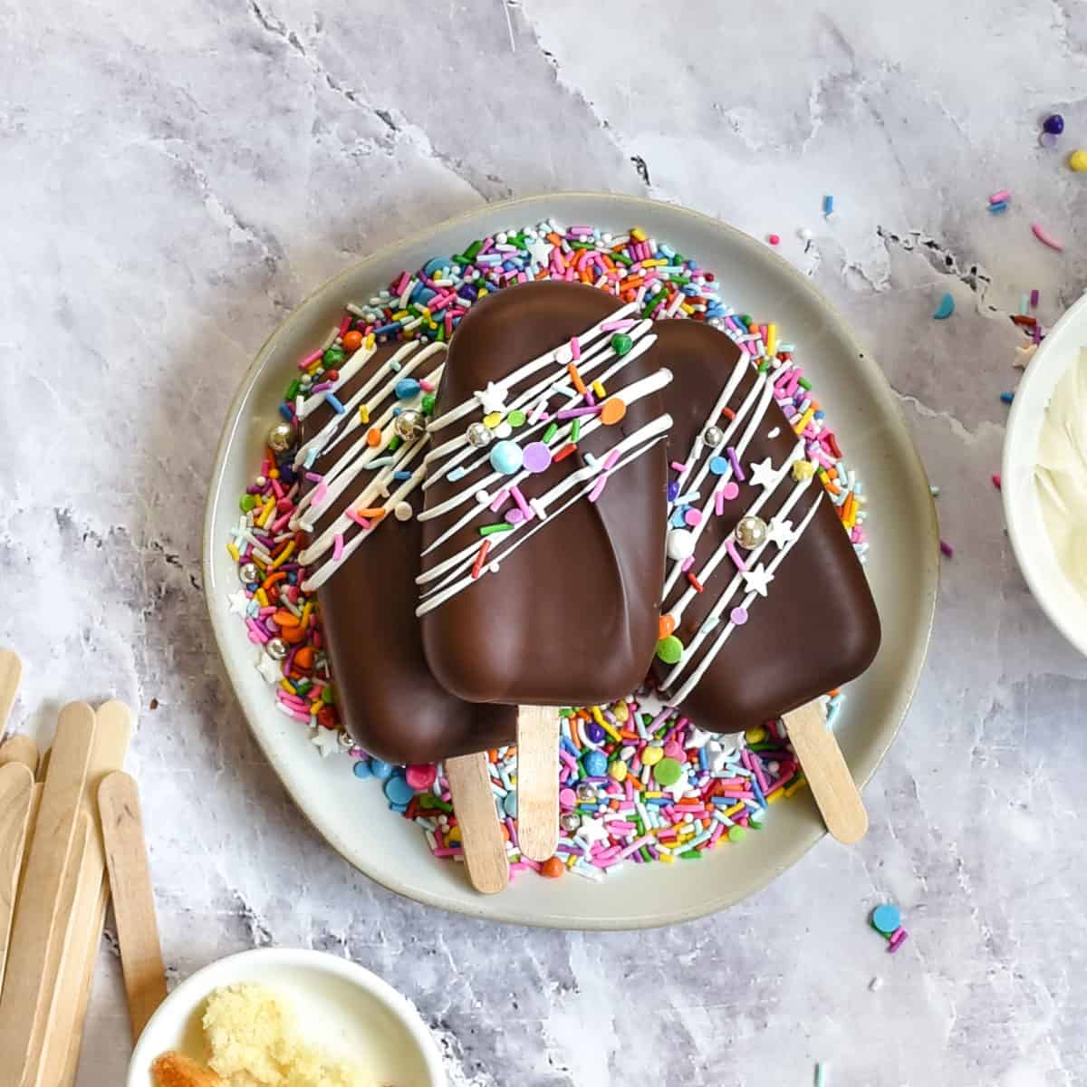 Finished cake popsicles on a plate with sprinkles.
