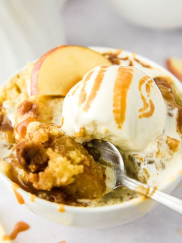 Caramel apple dump cake in a bowl with a spoon.