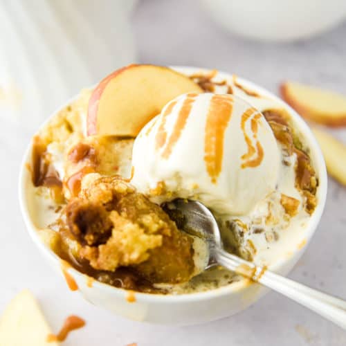 Caramel apple dump cake in a bowl with a spoon.