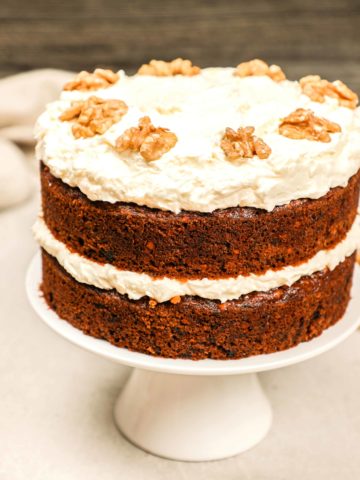 A carrot cake with raisins on a cake stand.