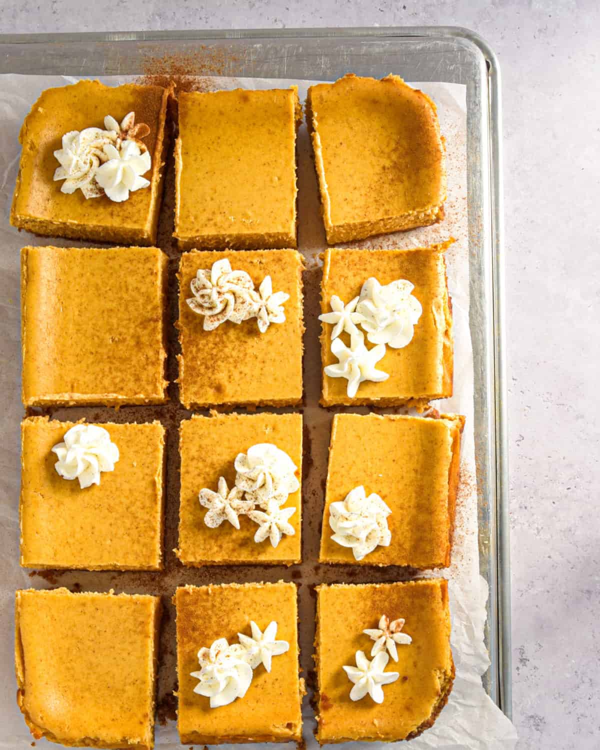 An overhead shot of pumpkin cheesecake bars cut into squares in a baking dish.