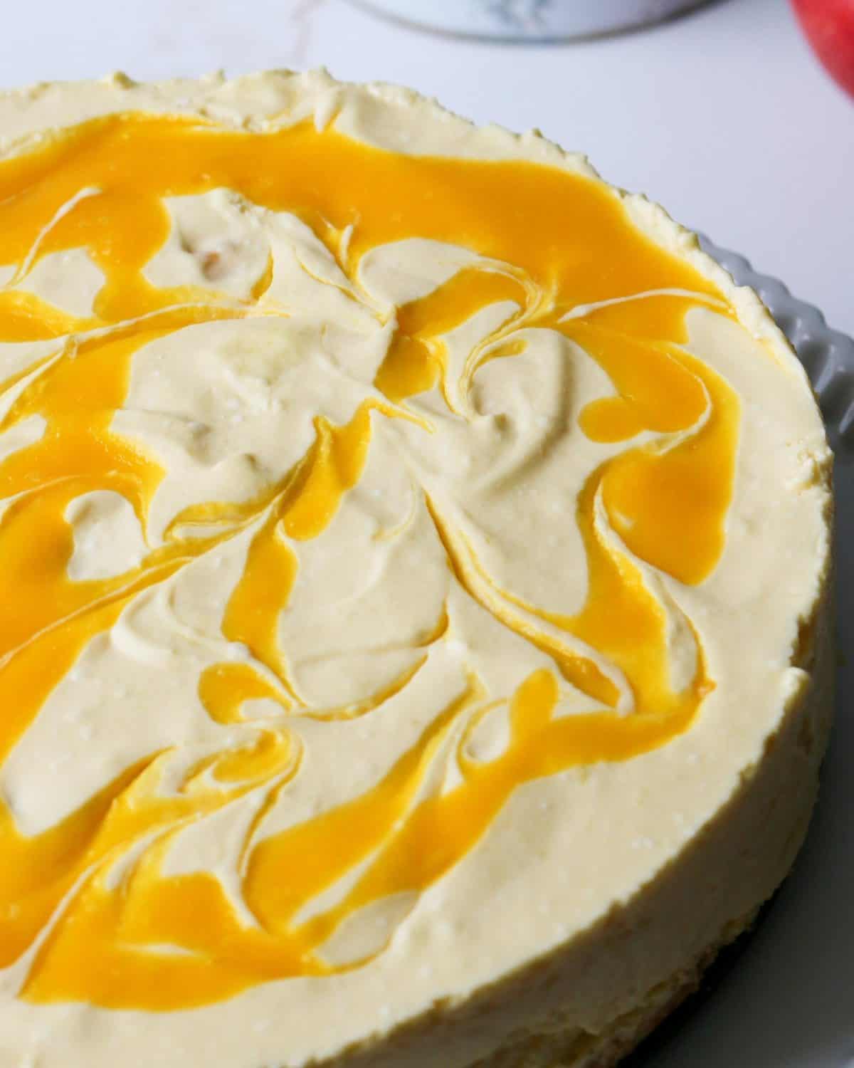 Mango swirls on top of a freshly made cheesecake.