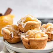 A pile of cinnamon roll apple pie cups on a plate.