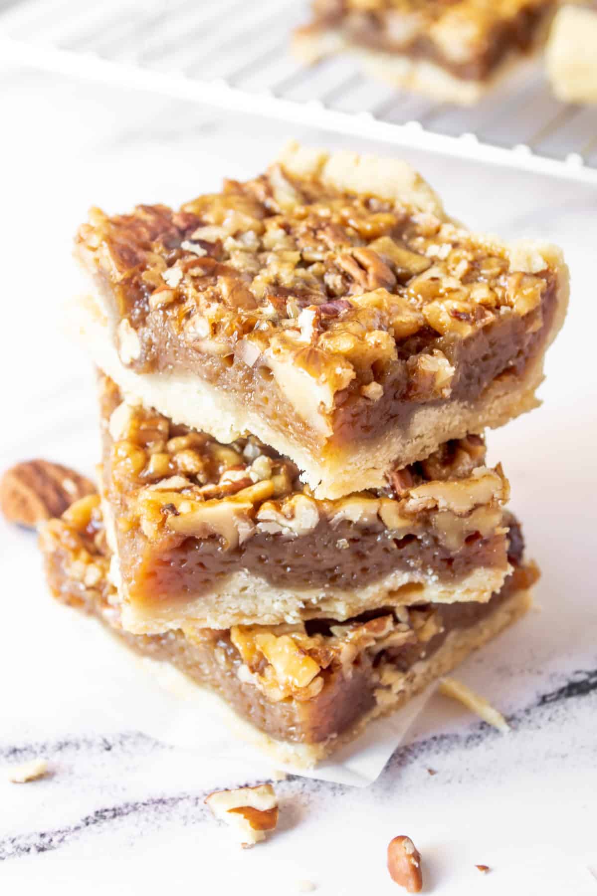 Three pecan pie bars stacked on top of each other.