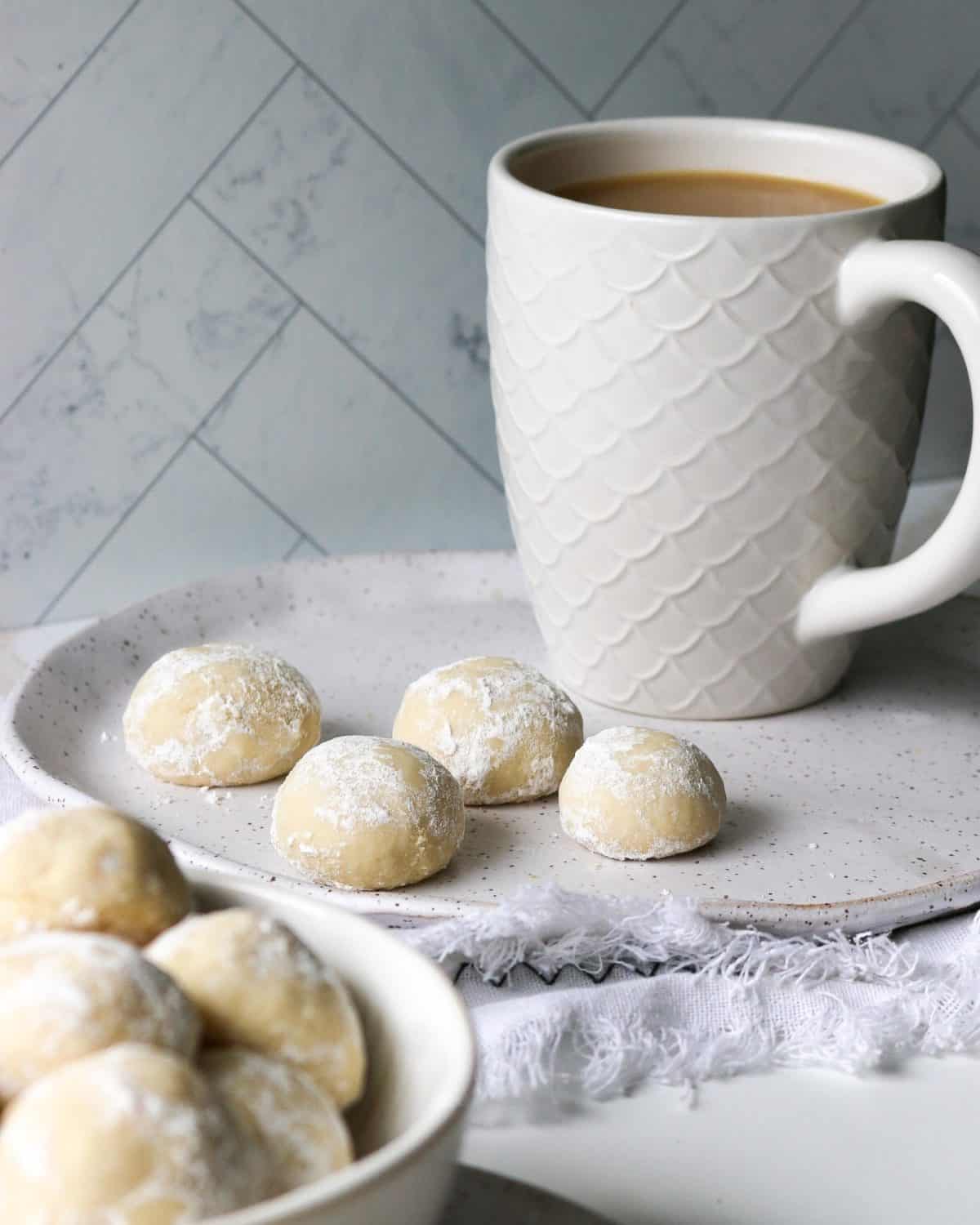 Powdered cookies with a fresh cup of hot coffee in the background.