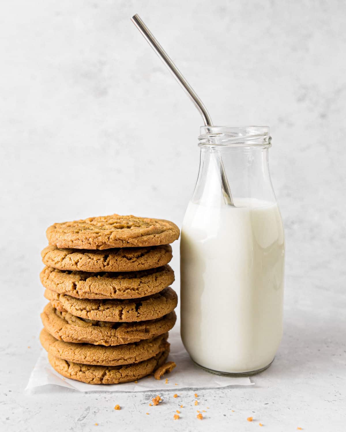 A stack of Biscoff butter cookies next to a glass jug of milk.