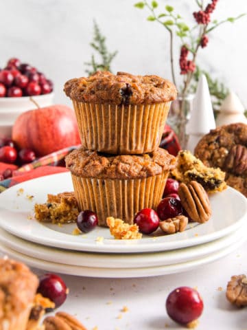 Two cranberry apple muffins on a white plate.