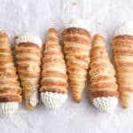 Several cream horns laying on parchment paper.