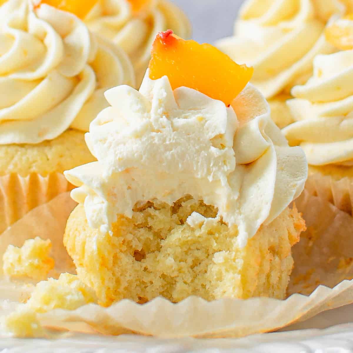 A peach cupcake with a bite taken out up close.