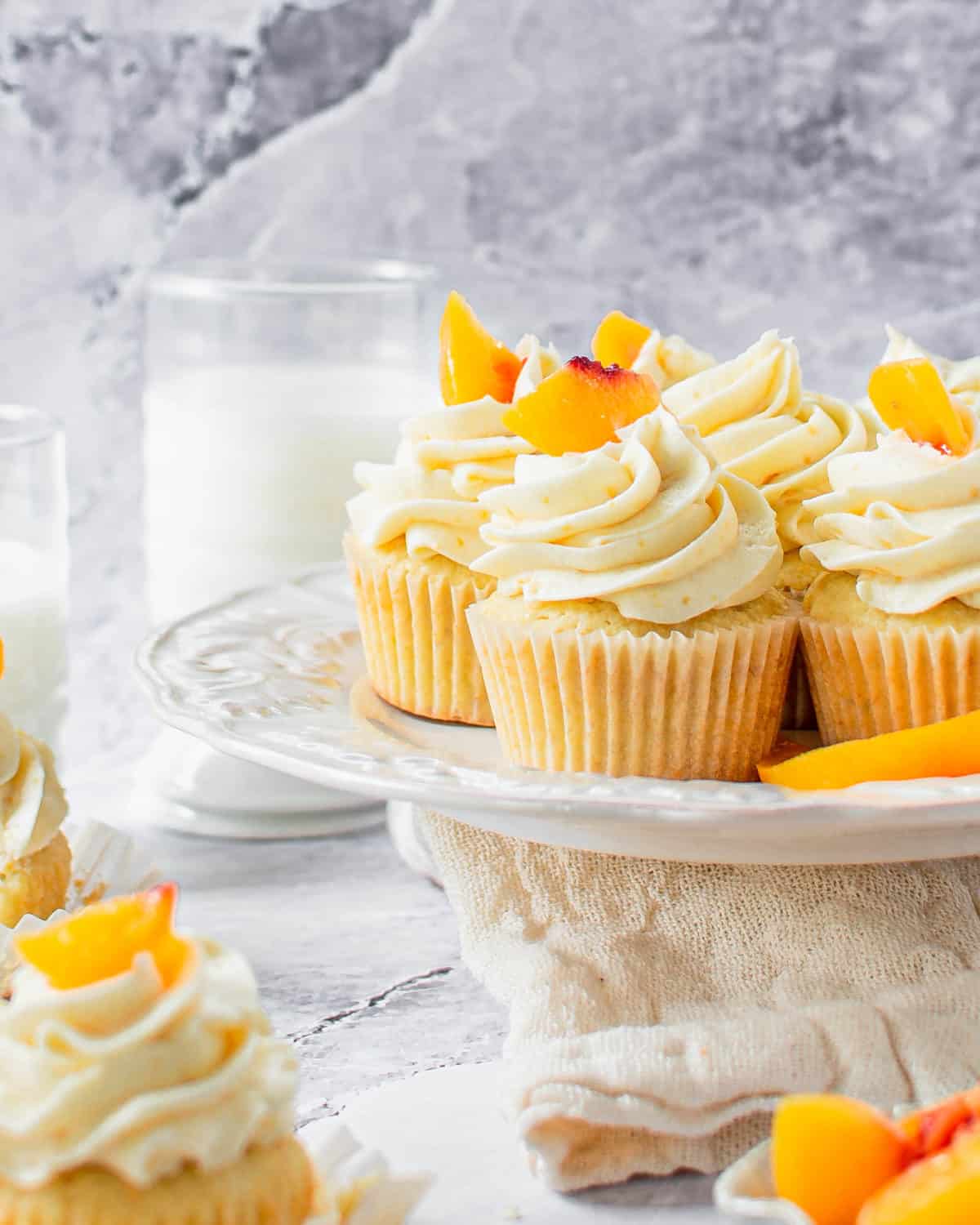 Several peach cupcakes on a cake stand.