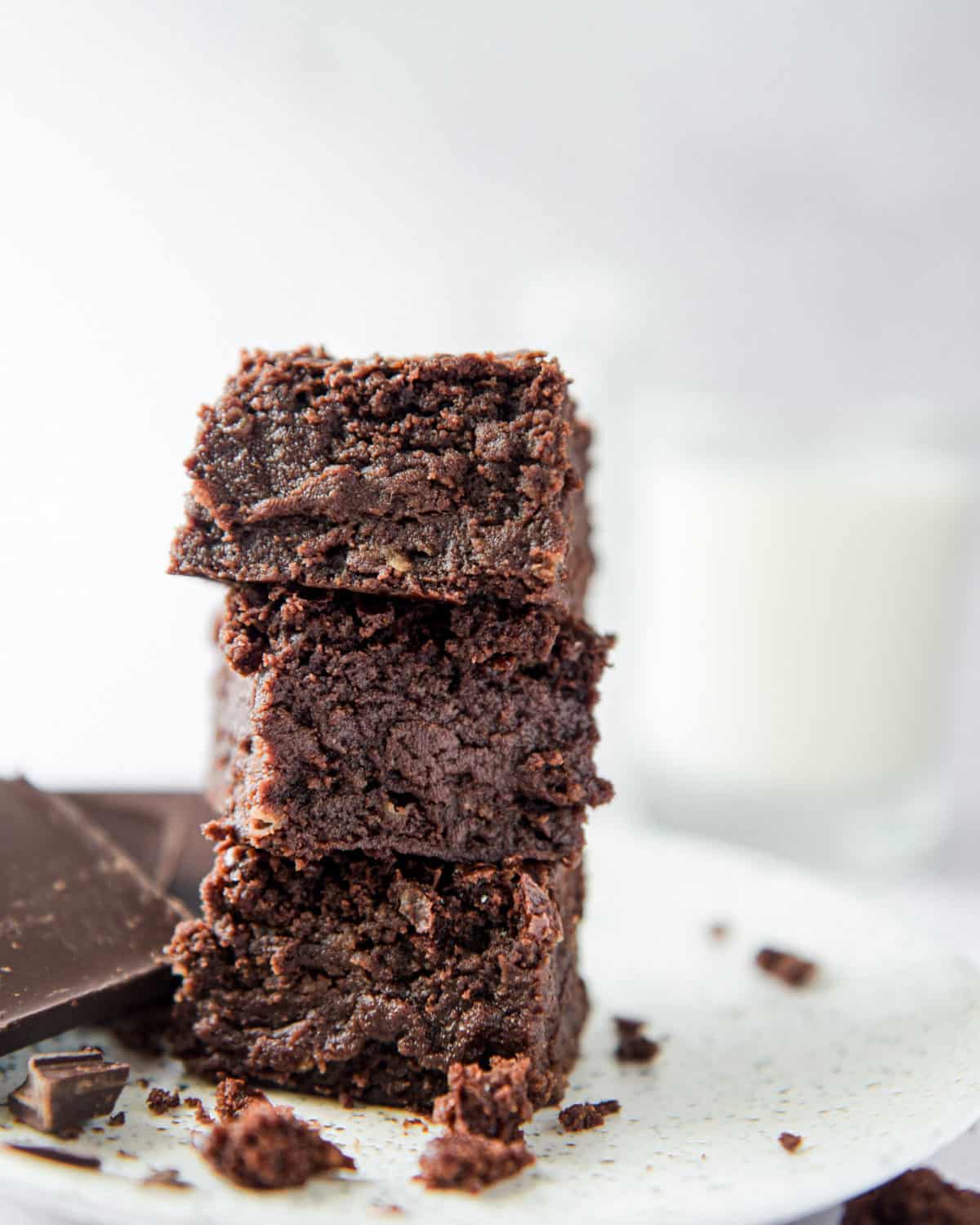 Eggless brownies in a stack surrounded by crumbs.