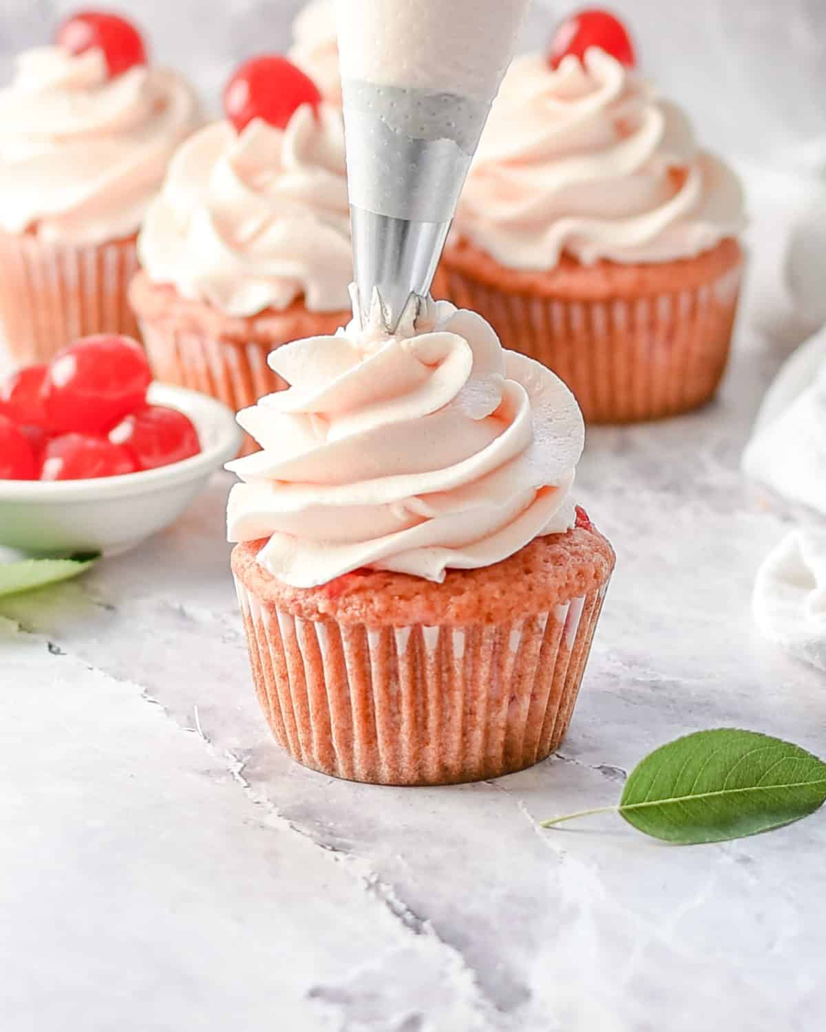 Piping frosting onto a cupcake.