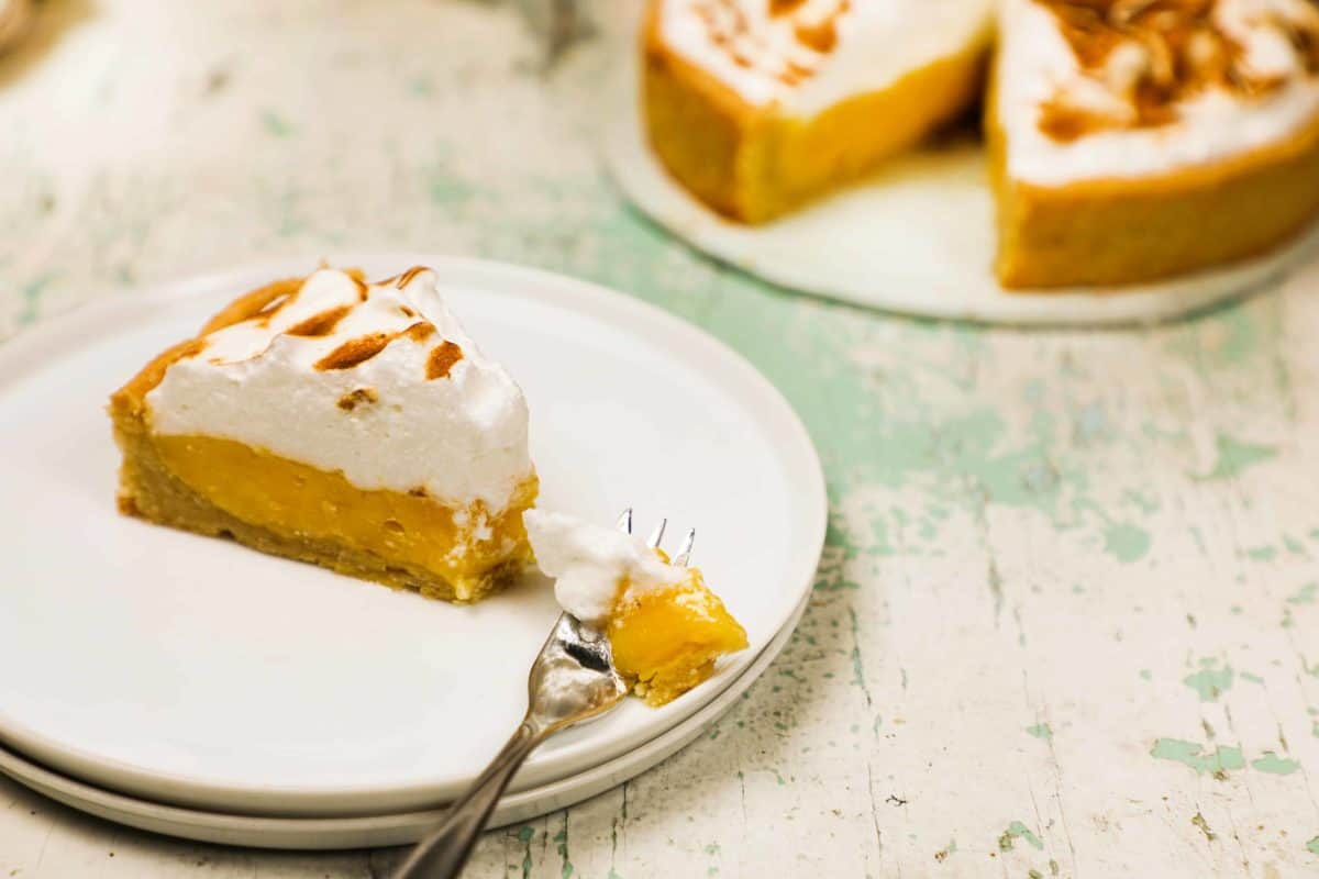 A slice of grandma's lemon meringue pie on a plate with a fork.