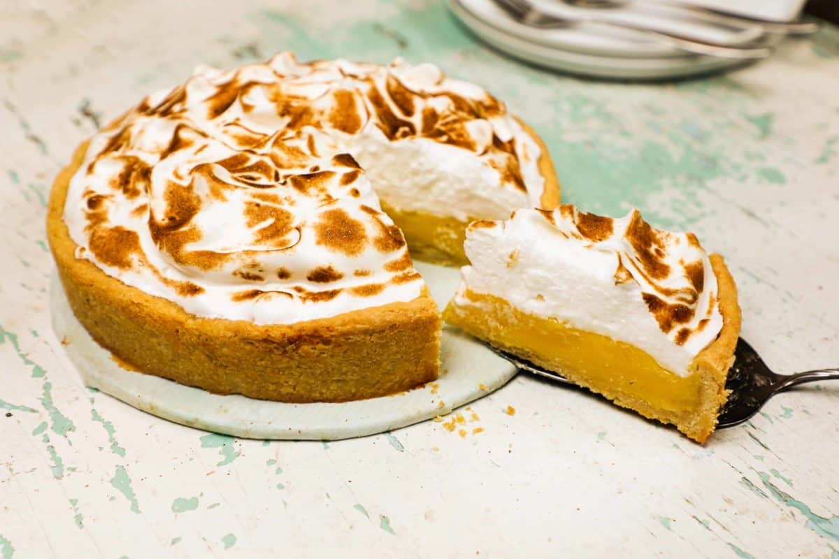 A slice of lemon meringue pie being served with a cake server.