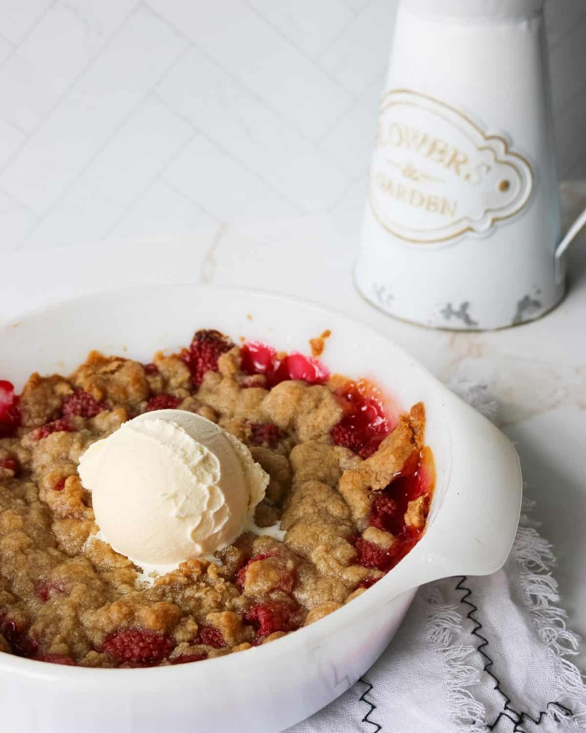 Raspberry crisp in a bowl topped with vanilla ice cream.