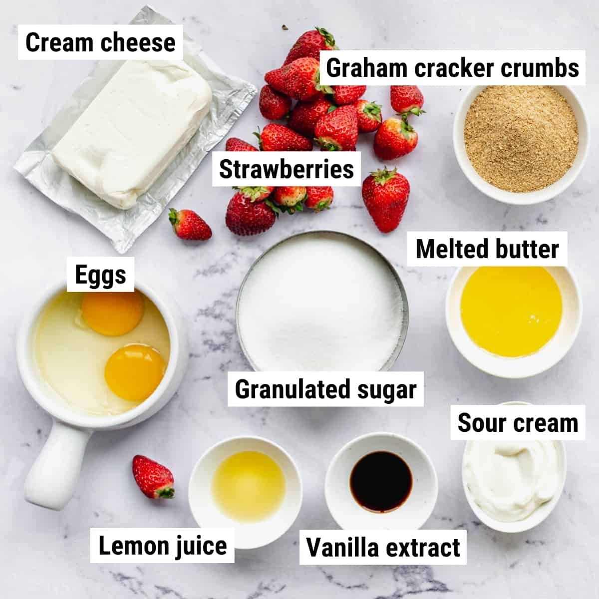 The ingredients to make mini strawberry cheesecakes on a table.