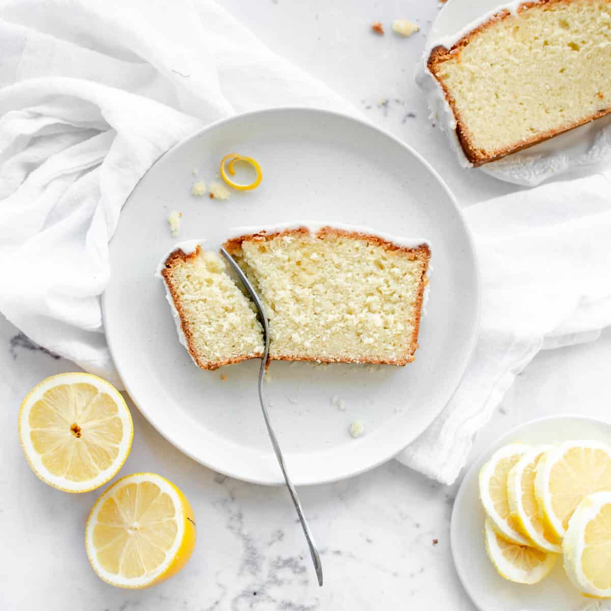 A slice of lemon pound cake on a plate with a fork.