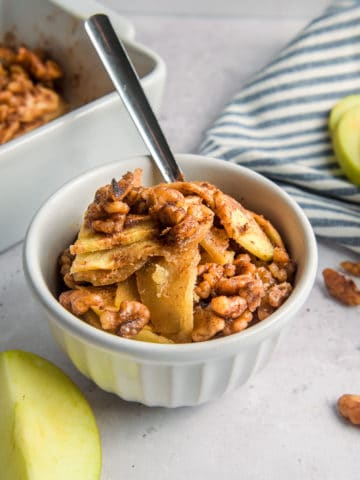 A bowl of keto apple crisp with a spoon in it.