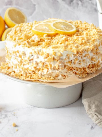 A lemon crunch cake on a cake stand.