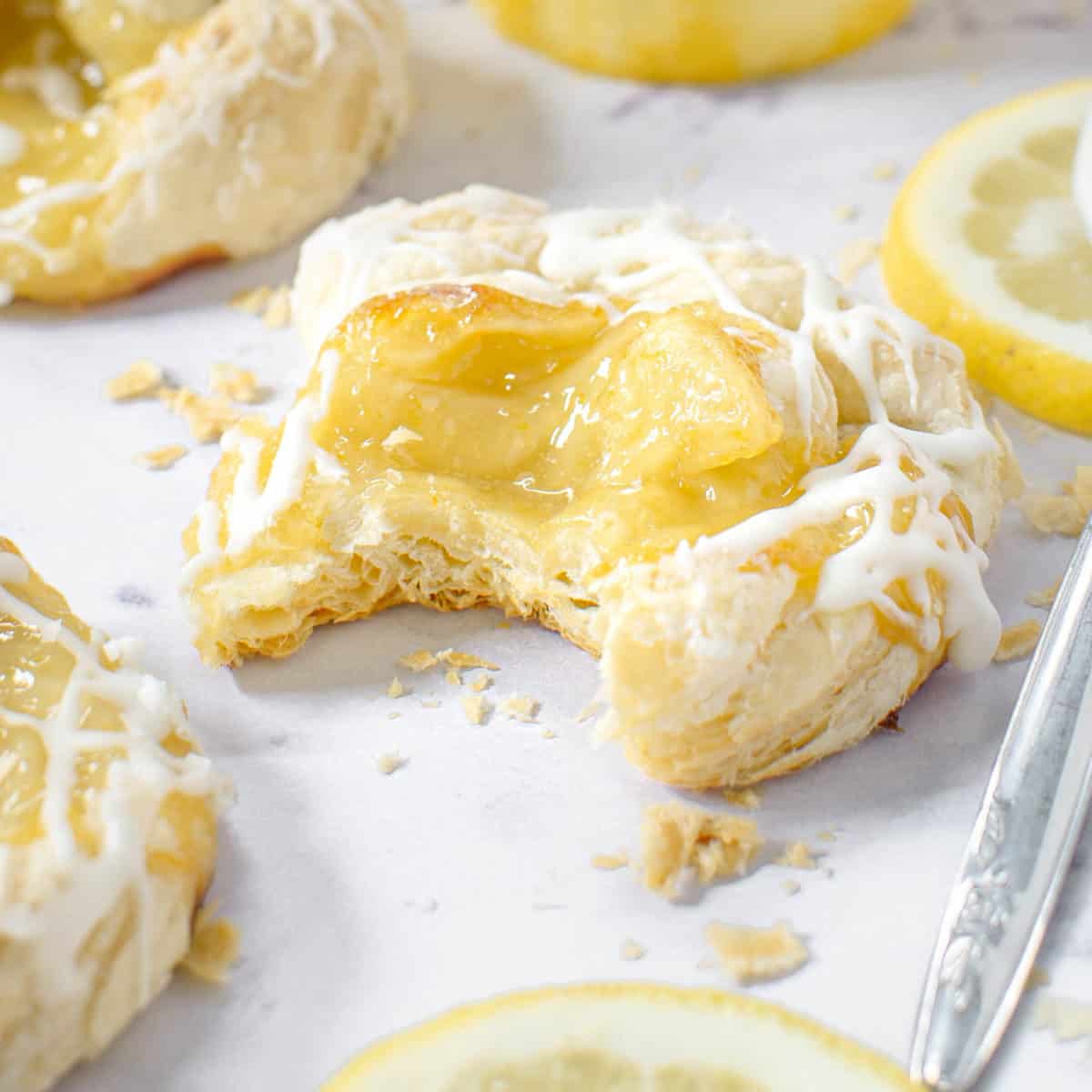A close up of a lemon curd puff pastry with a bite taken out of it.