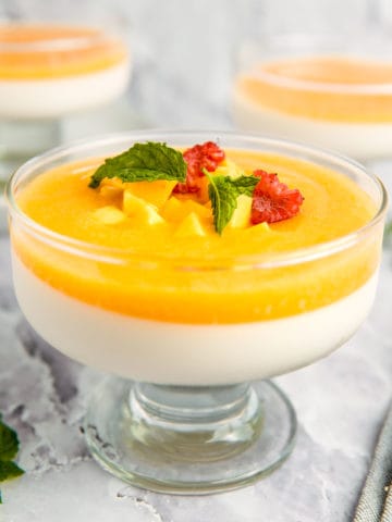 A glass dessert bowl filled with mango panna cotta.